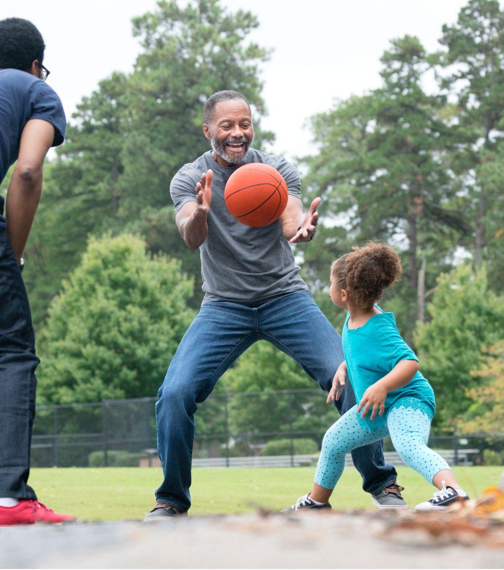 A man and a young girl playing basketball